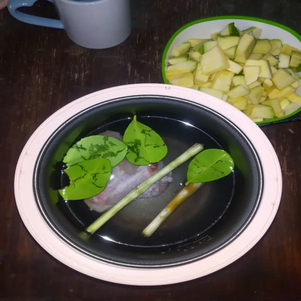 Rebus daun jeruk, sereh dan ayam dalam rice cooker hingga air mendidih.