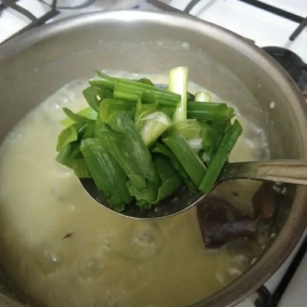 Masukan irisan bawang daun, masak hingga bubur kental dan matang