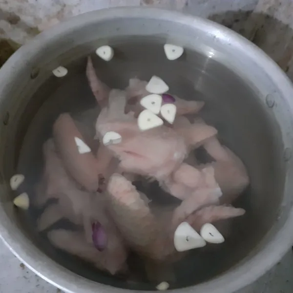 Rebus sayap ayam dalam 1,5 liter air, bersama dengan bawang putih, bawang merah, dan jahe cincang.