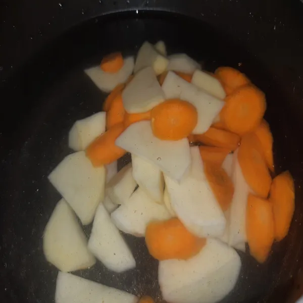 Tuang air ke dalam panci. Masukkan wortel dan kentang, masak hingga mendidih. Kemudian, masukkan bumbu halus yang sudah ditumis.