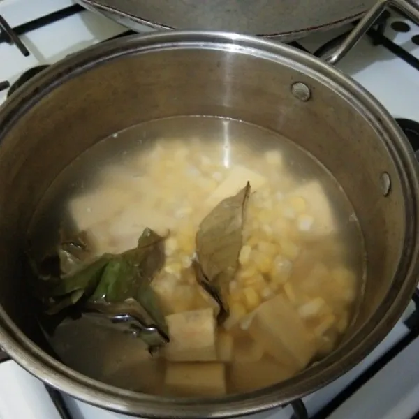 Didihkan air beserta daun salam, masukan jagung manis dan ubi jalar masak hingga setengah matang