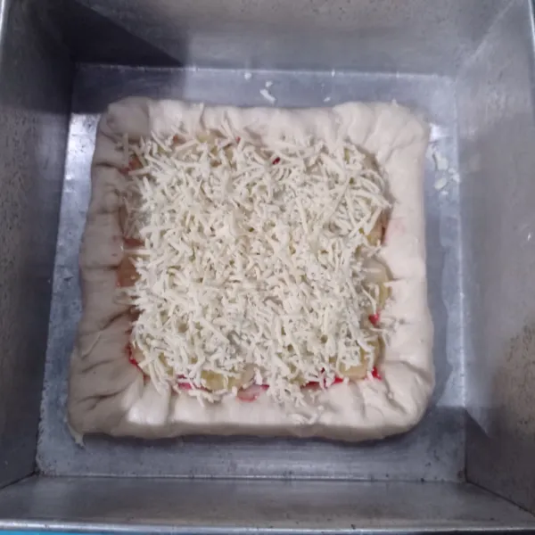Kempeskan adonan, bagi jadi dia lalu ratakan pada loyang sampai tipis, beri keju yang dipotong memanjang dibagian pinggiran lalu lipat adonan sampai keju tertutup, bagian tengah beri selai strawberry, tata pisang beri kental manis dan parutan keju cheddar