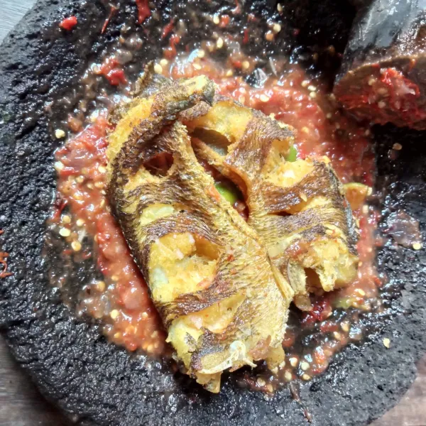 Letakkan ikan gabus goreng diatas sambal, lalu penyet dengan ulekan, siap disajikan.