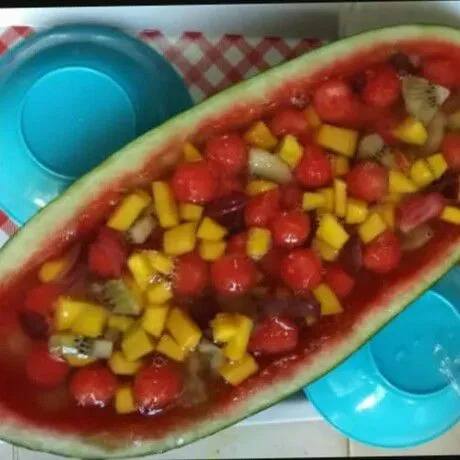 Masukkan buah-buahan ke dalam cekungan kulit semangka, aduk supaya menyebar.