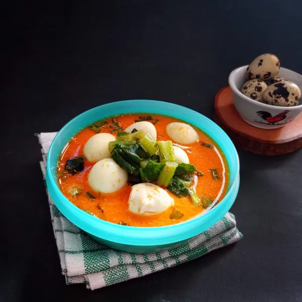 Tuang sayur batang kembang kol dan telur puyuh di mangkuk untuk disajikan.