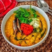 Salin bubur Manado ke mangkok dan sajikan dengan pelengkap.