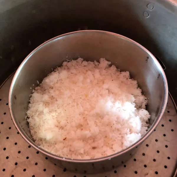 Panaskan kukusan, lapisi kukusan dengan kain agar uap tidak menetes. Letakkan kelapa parut di wadah tahan panas dan beri garam. Kukus sekitar 10 menit.