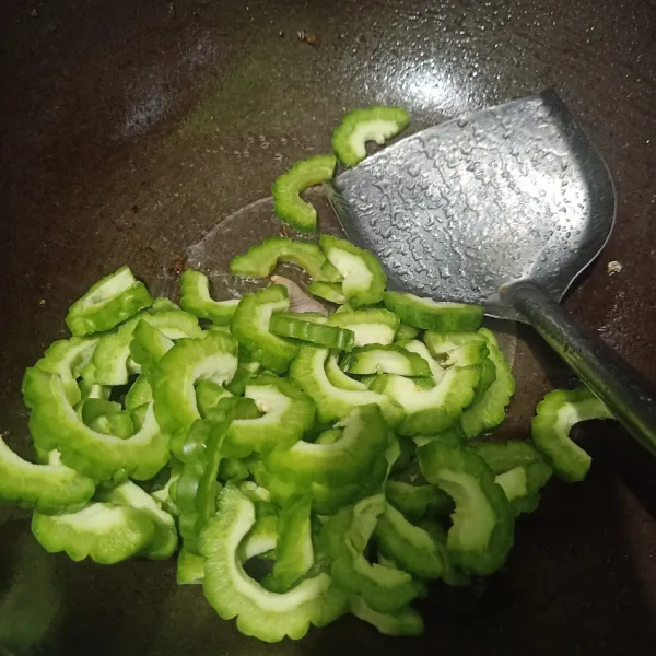 Masukkan irisan paria ke dalam wajan.