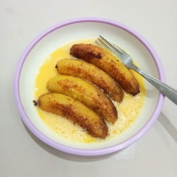Kemudian masukkan pisang ke dalam kocokan telur, baluri hingga rata.