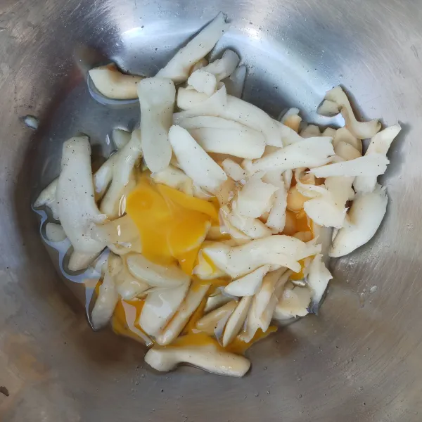 Suwir/iris kaki jamur tiram sesuai selera, kemudian cuci hingga bersih dan peras airnya. Tambahkan garam dan merica bubuk secukupnya, aduk rata. Kemudian tambahkan telur, aduk rata.