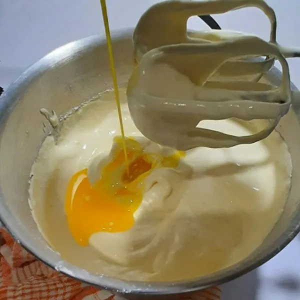Masukkan mentega yang sudah dilelehkan sedikit demi sedikit, mix dengan kecepatan rendah