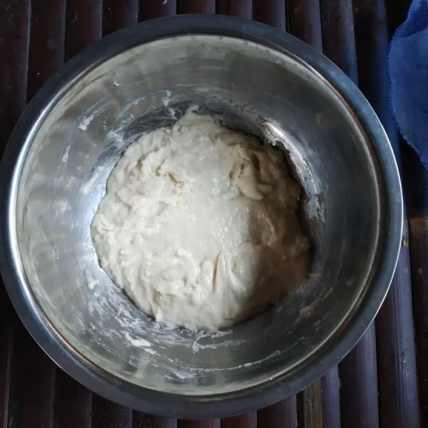 Tambahkan tepung terigu dan garam, aduk rata hingga tidak ada tepung yang masih kering. Diamkan selama 45 menit hingga mengembang.