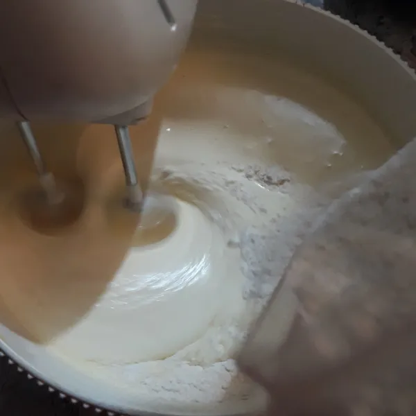 Turunkan kecepatan mixer menjadi sedang, tuang tepung terigu, maizena dan bubuk vanilla yang telah diayak terlebih dahulu.