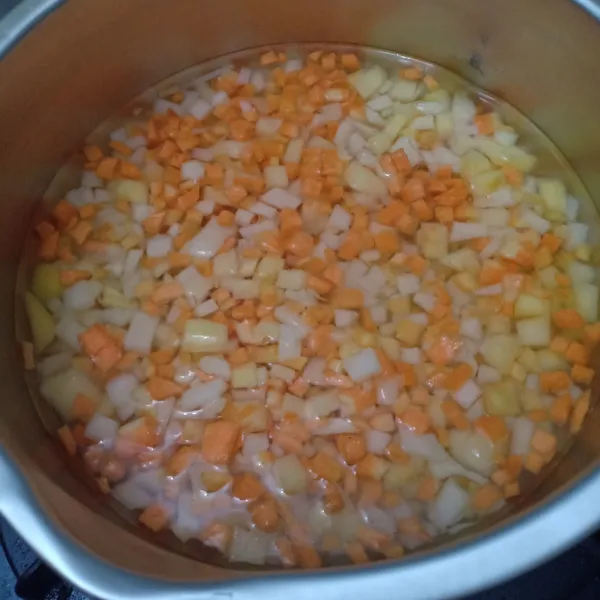 Potong dadu kecil kentang dan wortel, lalu tumis sampai matang.