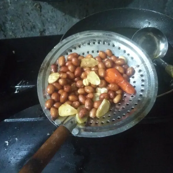 Goreng kacang tanah, cabai rawit dan bawang putih secara bergantian.