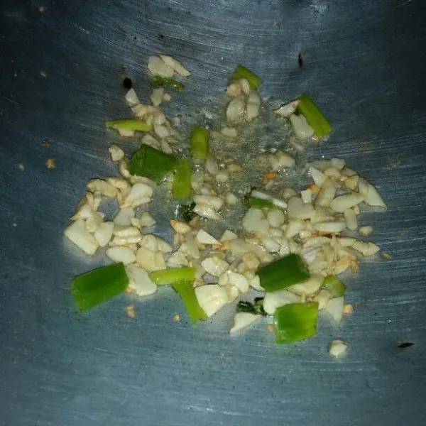Tumis bawang putih dan daun bawang sampai harum.
