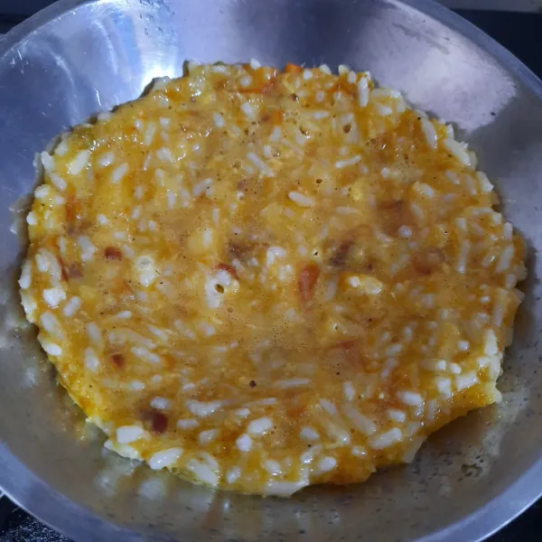 Setelah surut, masukkan kocokan telur dan bumbu (step 4). Aduk rata bersama nasi. Ratakan ke wajan tapi jangan terlalu tipis. Masak hingga bagian bawah kecokelatan.