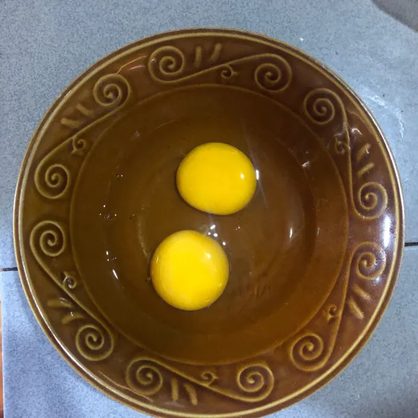 Pecahkan 2 butir telur ke dalam mangkok.