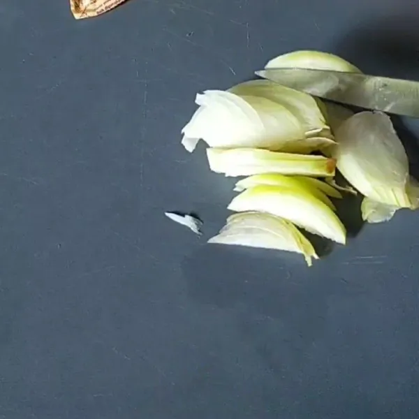 Iris tipis-tipis bawang bombay dan bawang putih.
