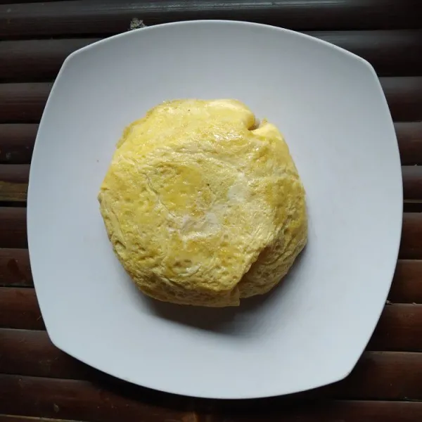 Balikkan mangkok di atas piring, gunting bagian atas telur dadar agar nasi terlihat, sajikan hangat.
