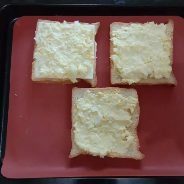Siapkan roti tawar oles dengan mentega, beri keju slice dan tumpuk dengan telur yang dihaluskan.