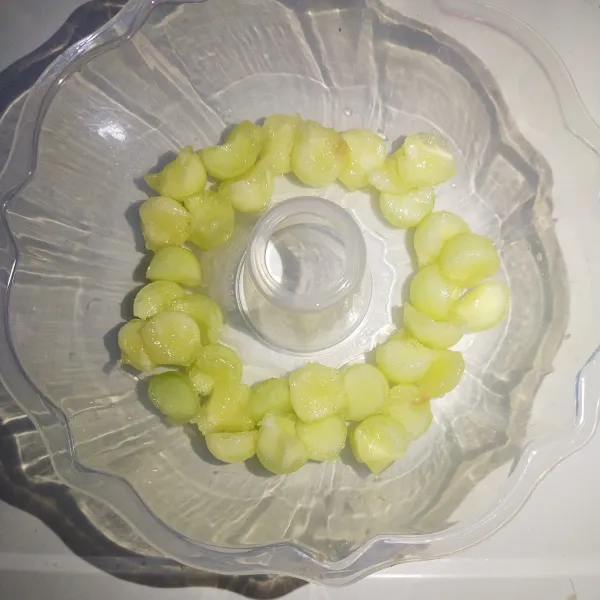 Buah melon yang dibentuk bulat bulat masukkan ke dalam cetakan puding