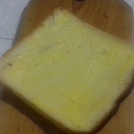 Ambil selembar kulit roti. Oles margarin pada bagian dalamnya.