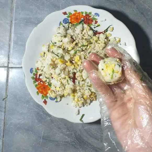 Hancurkan nasi kemudian campur dengan tumisan dan telur. Aduk-aduk dengan tangan, opsi lain masukkan ke dalam wajan seperti membuat nasi goreng. Ambil sedikit nasi campur kemudian kepal-kepal hingga bulat
