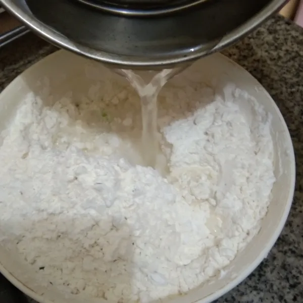 Tambahkan air panas secukupnya pada campuran tepung sedikit demi sedikit.