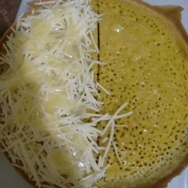 Setelah matang, pindahkan martabak pada talenan besar. Olesi dengan butter dan beri parutan keju lalu siram kental manis, Tutup kulit martabak, olesi kulit martabak dengan butter, potong-potong dan sajikan.