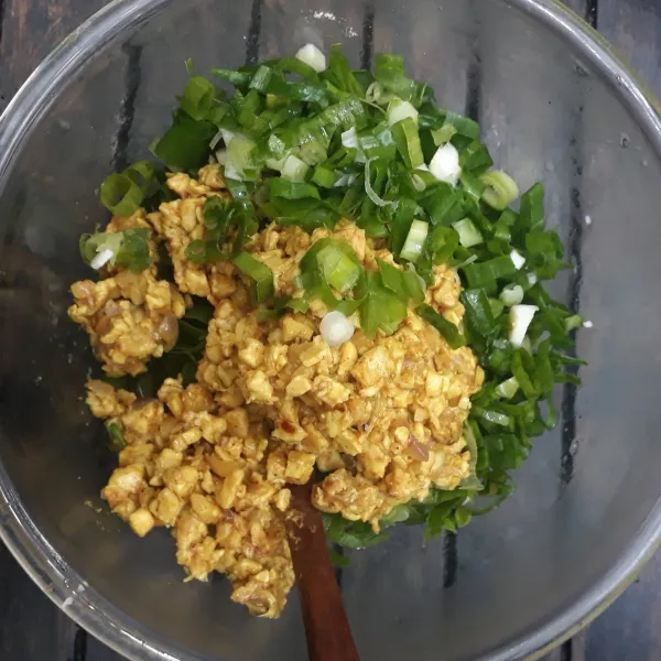 Masukkan tumis tempe bumbu kari dan irisan daun bawang ke dalam kocokan telur lalu aduk rata.