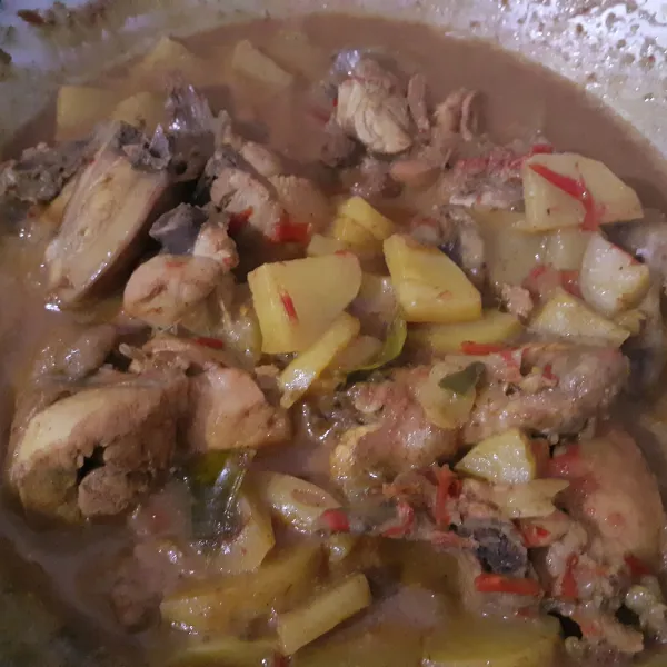 Masukkan ayam dan kentang, aduk rata. Tambahkan 250 ml air. Setelah mendidih, kecilkan api. Masukkan santan kental. Aduk terus agar santan tidak pecah. Masak sampai mendidih. Koreksi rasa dan sajikan.