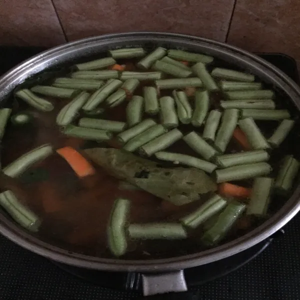 Masukan tumisan bumbu ke dalam air rebusan daging bersama wortel dan buncis masak sampai sayuran setengah matang