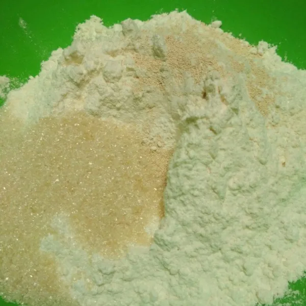 Dalam wadah campur tepung terigu, gula pasir dan ragi instan aduk rata