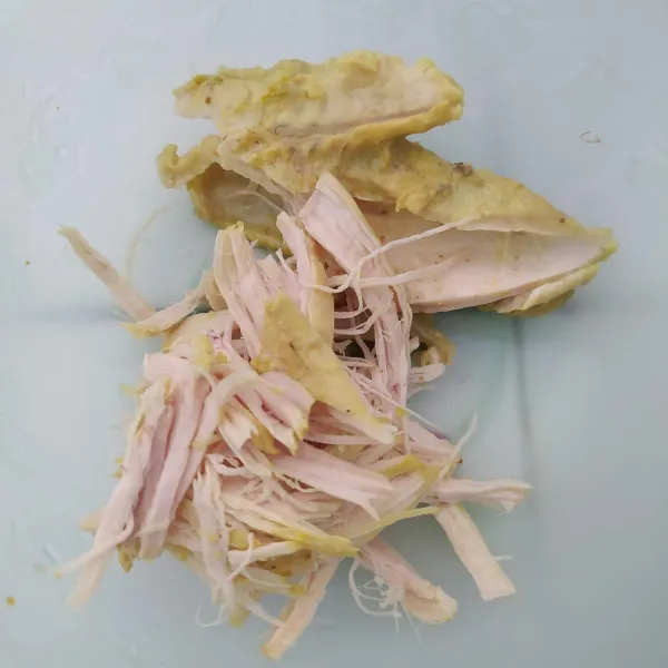Ambil daging ayamnya, kemudian suwir-suwir. Sajikan bubur nasi dengan tambahan ayam suwir dan kuah opor serta pelengkap lainnya.