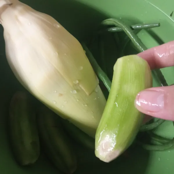 Kupas jantung pisang buang kulit merahnya hingga tersisa bagian putihnya saja. Kupas kulit terluar pisang hingga tersisa seperti di foto. Potong jantung pisang lalu rendam di dalam air agar tidak menghitam.