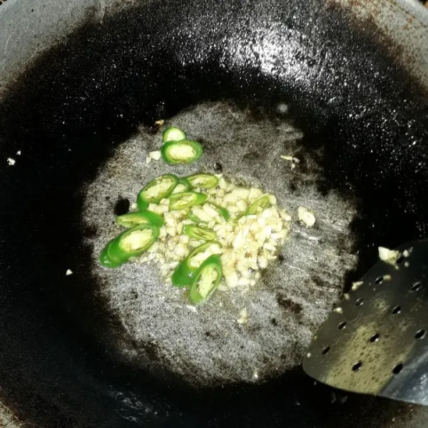 Panaskan minyak goreng, lalu tumis bawang putih dan cabe hingga harum.