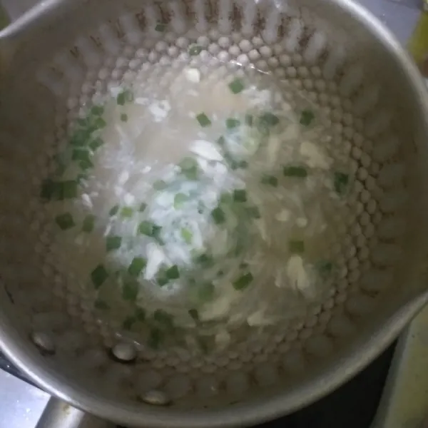 Masak air, garam, kaldu jamur, bawang putih dan daun bawang. Rebus sampai air mendidih.