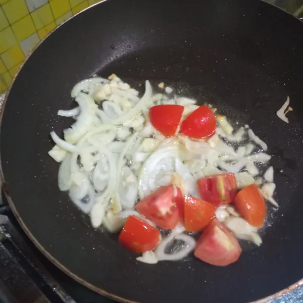 Tumis bawang merah dan bawang putih hingga harum, lalu masukkan tomat. Tumis sebentar sambil diaduk.