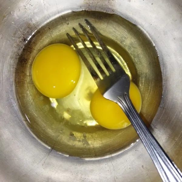 Siapkan 2 butir telur, pecahkan tuang ke mangkuk, beri sejumput garam. Kocok dengan garpu hingga berbusa.
