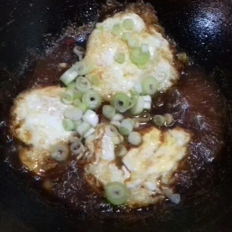 Masukkan telur ceplok dan irisan daun bawang. Masak hingga bumbu meresap kemudian matikan api. Angkat dan sajikan, siap dihidangkan dengan nasi putih hangat.