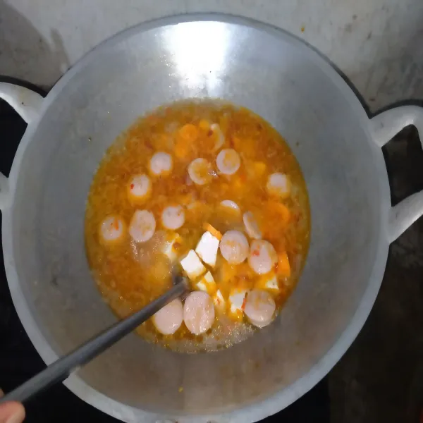 Terlebih dahulu masukkan tahu, sosis dan wortel. Masak hingga mendidih.