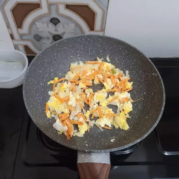 Masukkan telur, tumis sebentar, lalu masukkan wortel. Tambahkan sedikit air. Masak hingga wortel empuk. Tambahkan irisan daun kol.