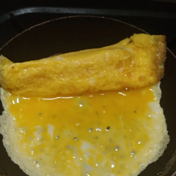 Tambahkan telur kocok pada bagian telur yang sudah setengah matang. Gulung dan lakukan berulang sampai kocokan telur habis.