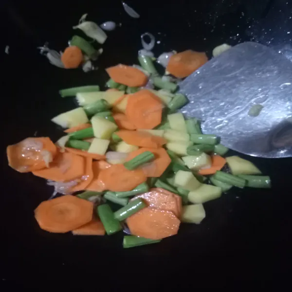 Tumis bawang merah dan bawang putih sampai harum lalu masukkan wortel, buncis dan kentang. Aduk rata.