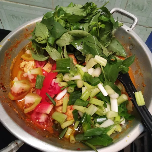 Setelah kuah menyusut dan bumbu meresap, masukkan daun bawang, daun kemangi dan tomat iris. Aduk rata.