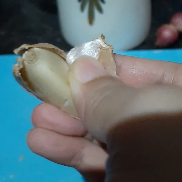 Lepaskan kulit bawang putih dengan menariknya dari buah bawang menggunakan tangan. Bawang putih kupas siap digunakan.