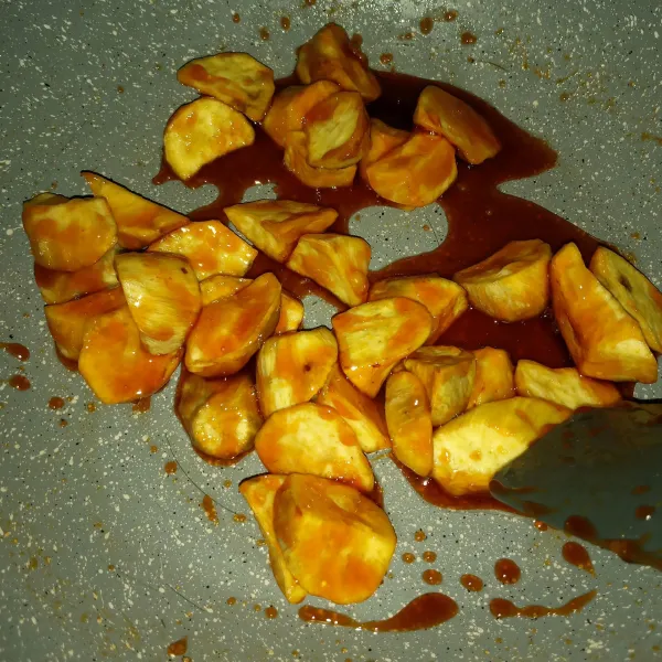 Matikan api lalu masukkan ubi goreng, aduk menggunakan dua spatula dengan cepat sampai terbalut semua.