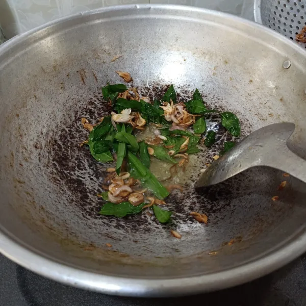 Panaskan minyak goreng, tumis bawang merah iris sampai harum dan kecoklatan. Masukkan daun kari dan daun pandan, tumis sampai harum.