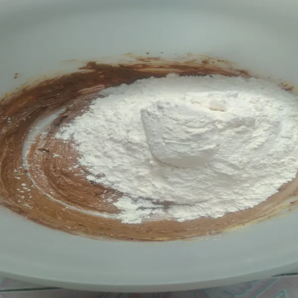 Setelah rata masukkan tepung terigu sedikit demi sedikit, lalu kocok hingga adonan kalis.